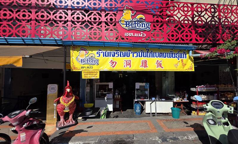 หน้าร้านเจริญข้าวมันไก่เบตงพันธุ์แท้ ป้ายเหลืองและรูปปั้นไก่แดงหน้าร้าน
